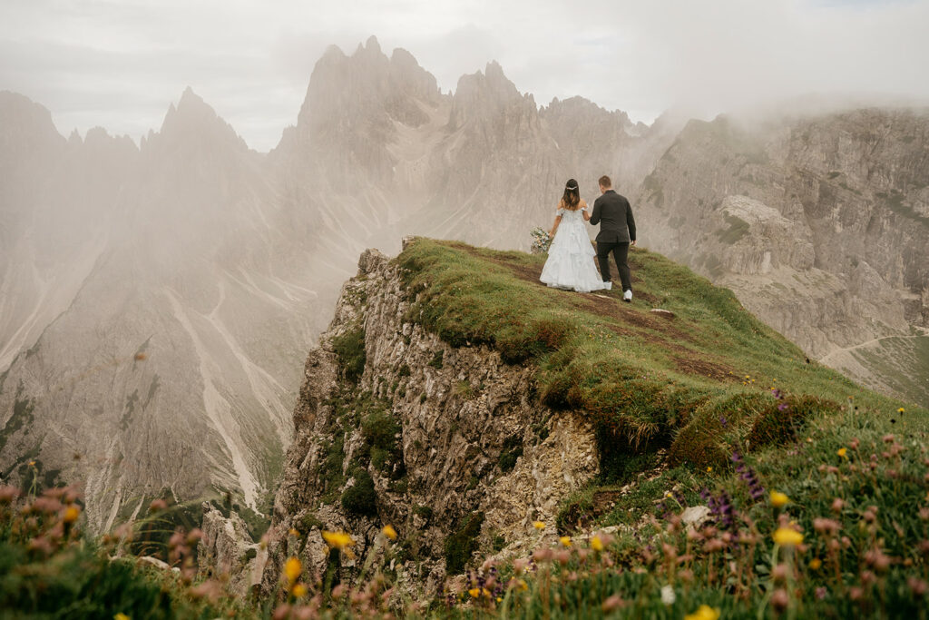 Bride and groom walking on mountain edge