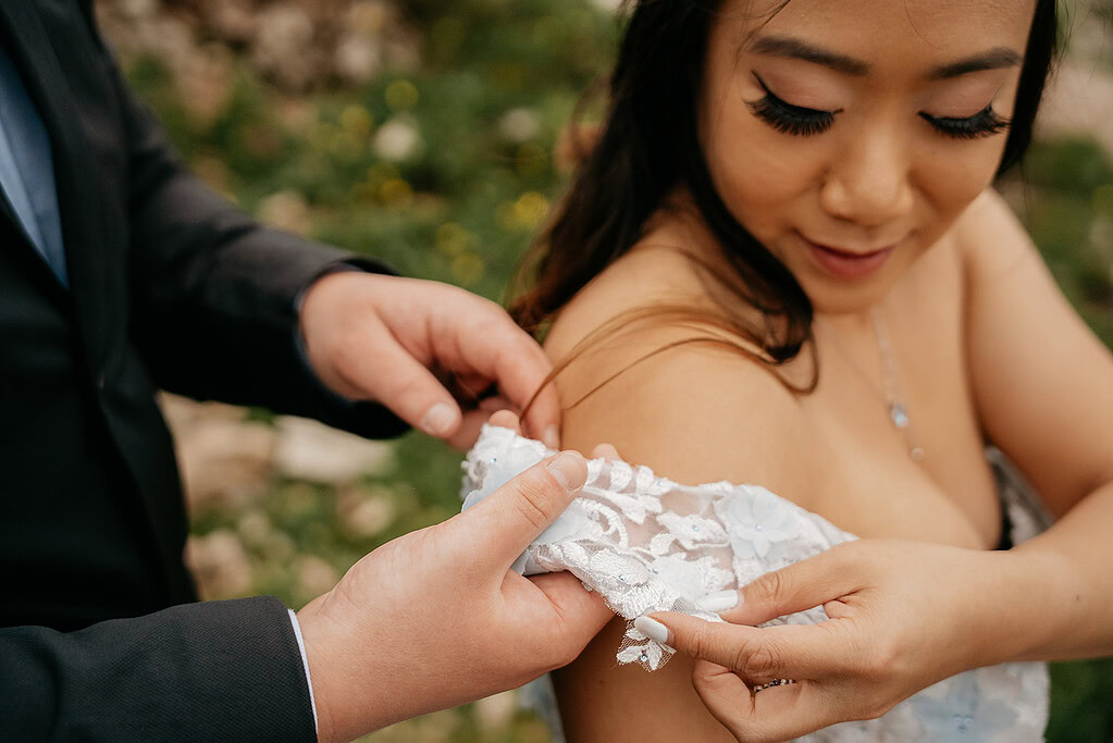 Person adjusting floral lace dress strap outdoors.