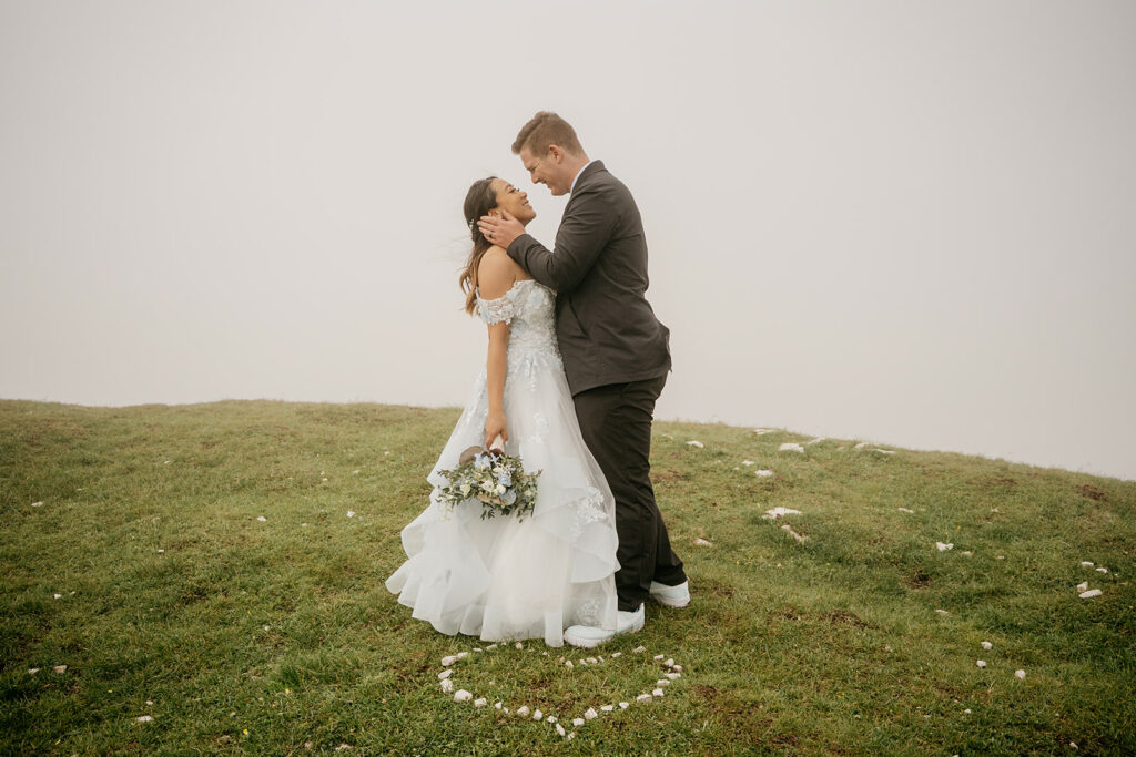 Bride and groom embrace on grassy field