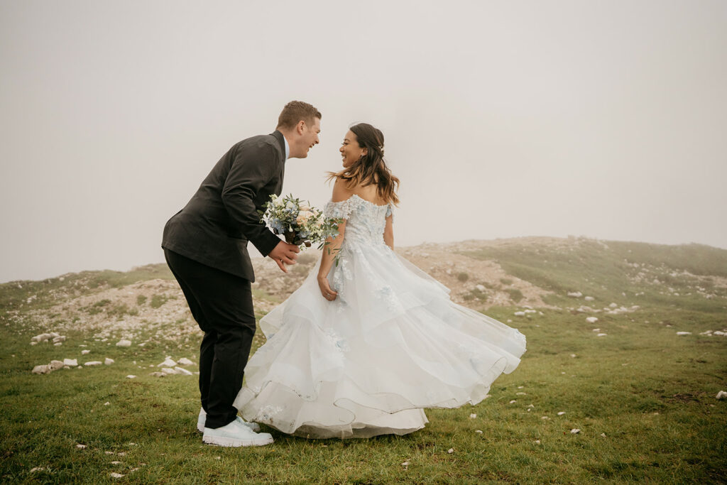 Bride and groom laughing in misty mountain landscape