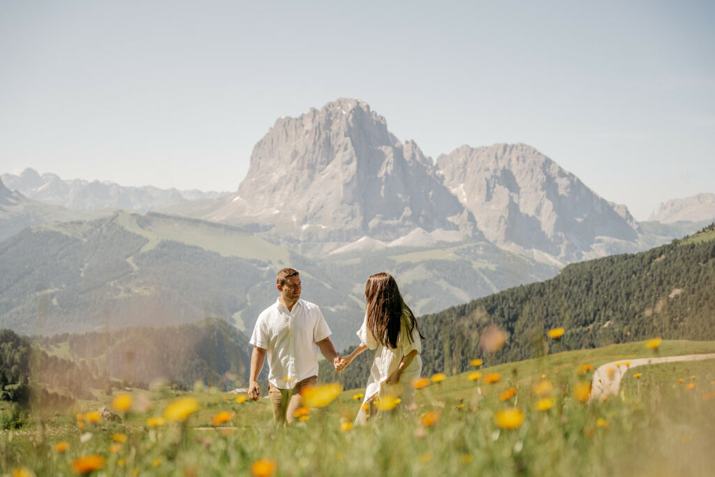 Couple walking in mountain meadow with flowers.