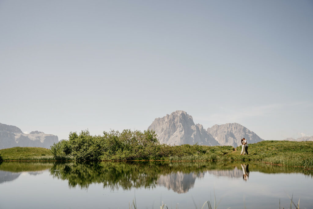 Couple embraces by mountain lake reflection