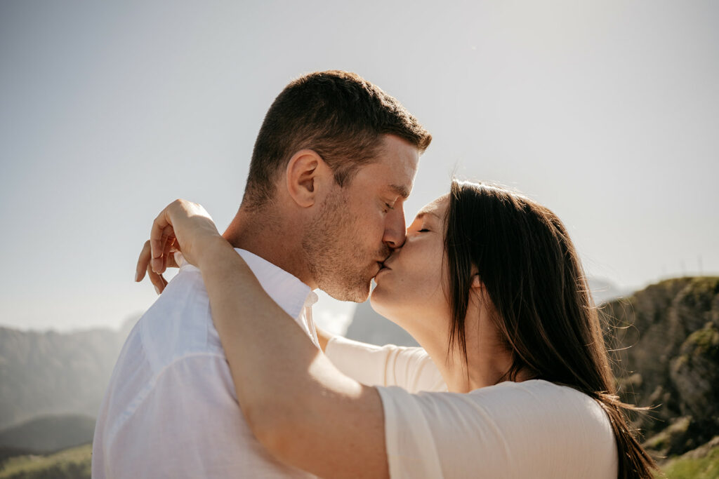Couple kissing outdoors with mountains in background