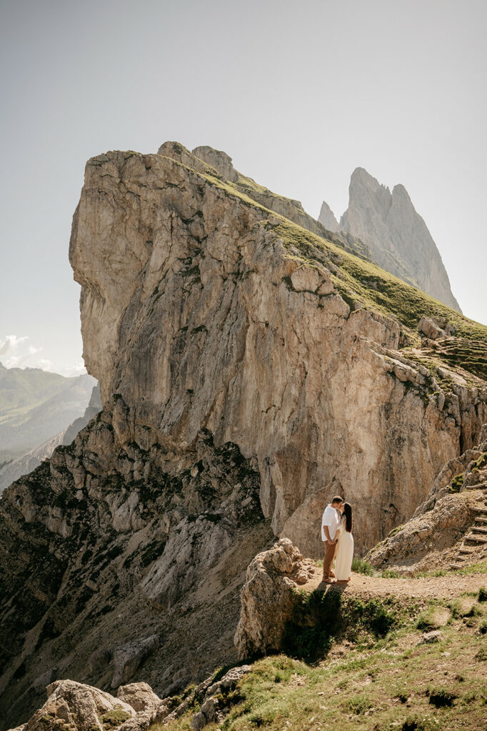 Couple embraces on mountain cliff edge.