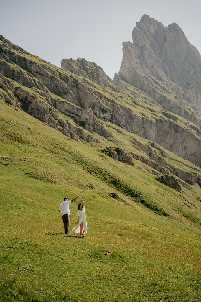 Couple dancing on mountain slope with scenic view.