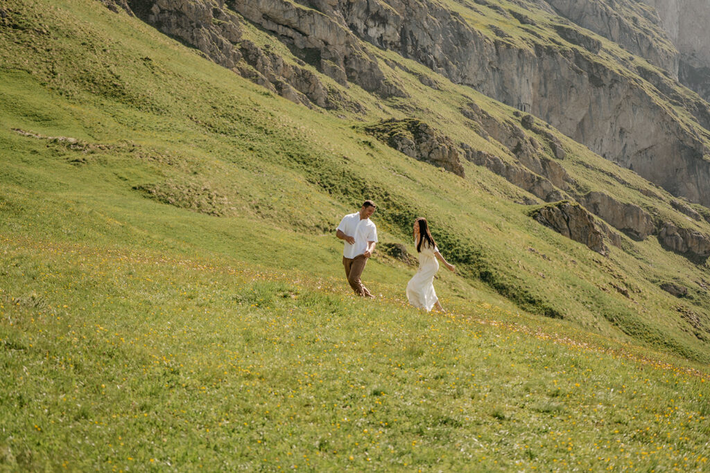 Couple running on grassy mountain slope