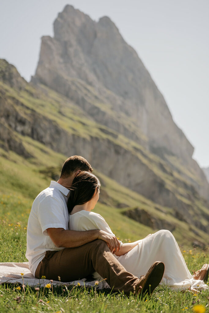 Couple sitting on grassy hillside near mountains