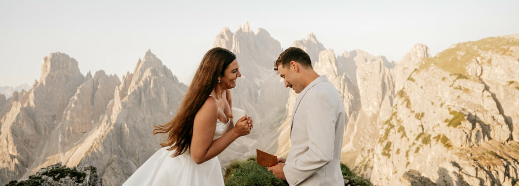 Bride and groom exchange vows in mountain setting.