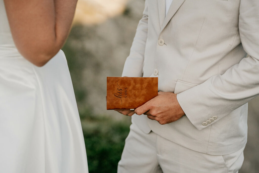 Groom holding vow book at wedding ceremony.