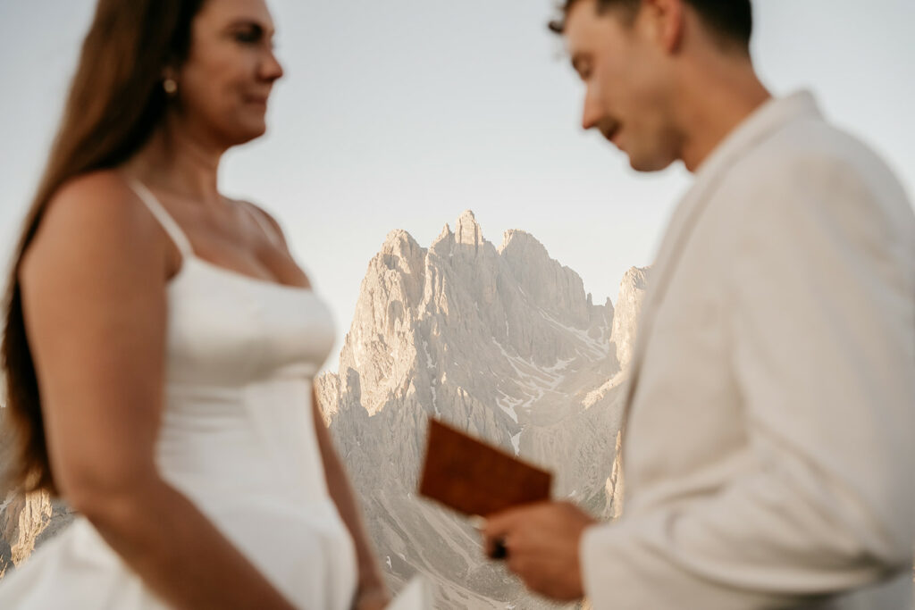 Couple exchanging vows with mountain backdrop.