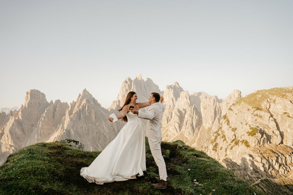 Couple embraces on mountain landscape during wedding.