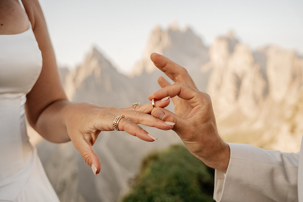 Couple exchanging rings in scenic mountain setting.