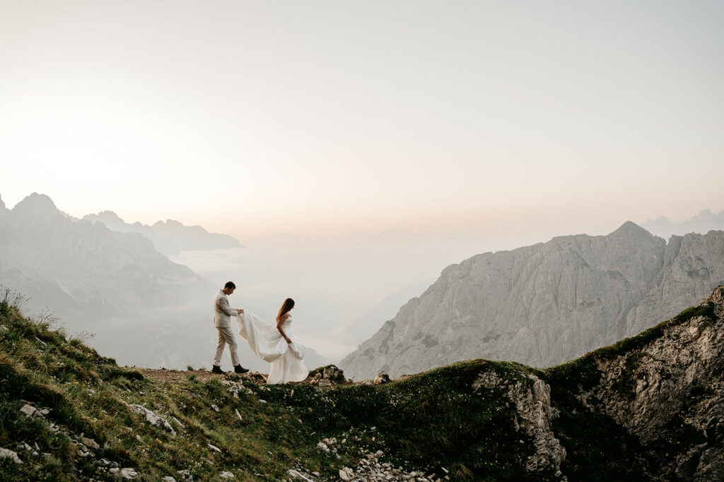 Couple hiking on mountain path at sunrise.