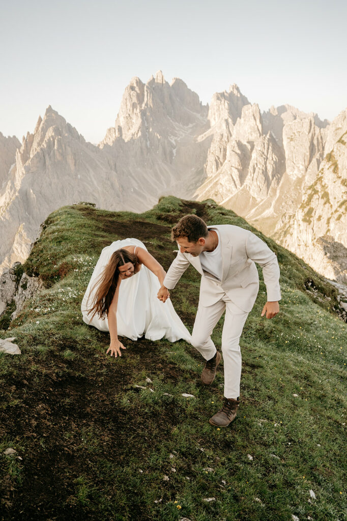 Couple hiking in mountains in wedding attire.