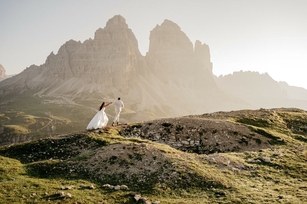 Couple in wedding attire on mountain landscape.