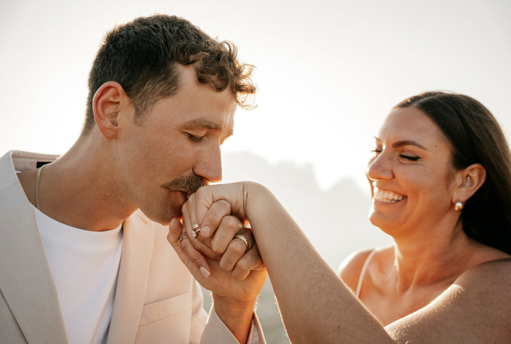 Man kisses woman's hand, both smiling.