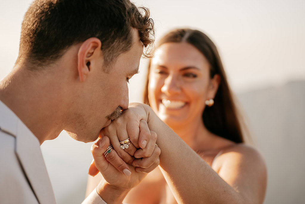 Man kissing woman's hand, showing engagement rings.
