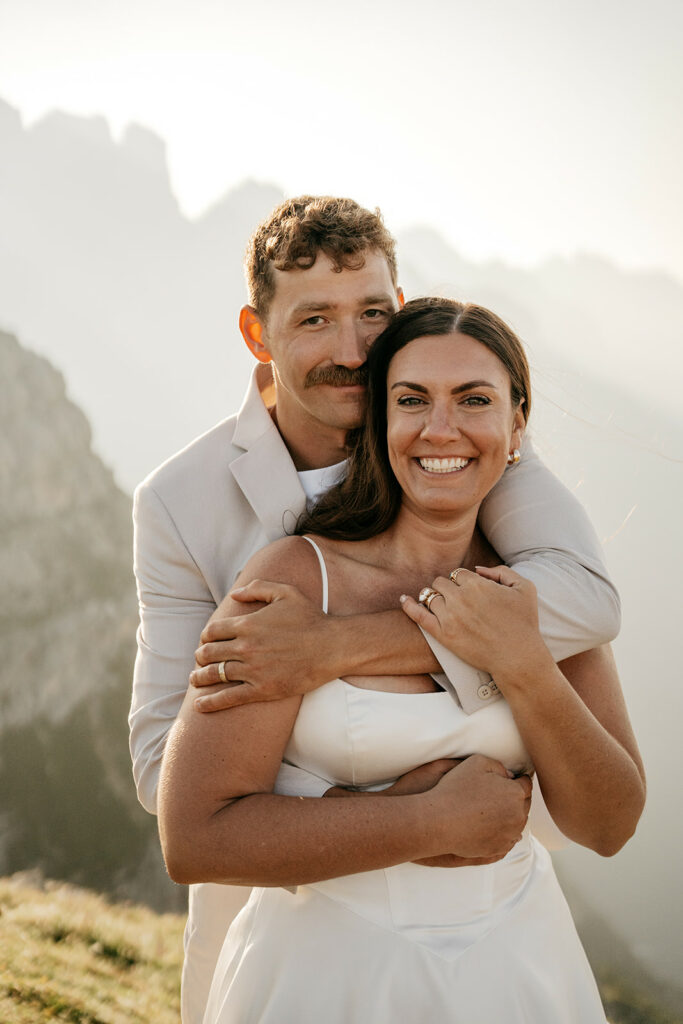 Smiling couple embracing during mountainous outdoor wedding.