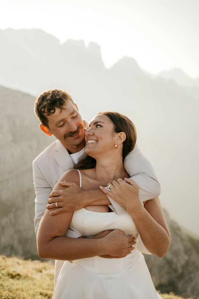 Couple embracing in mountain landscape during sunset.