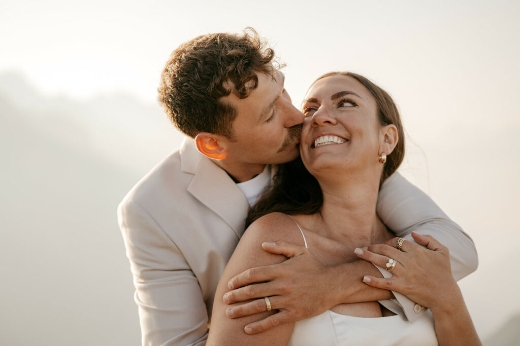 Couple embracing and smiling affectionately outdoors.