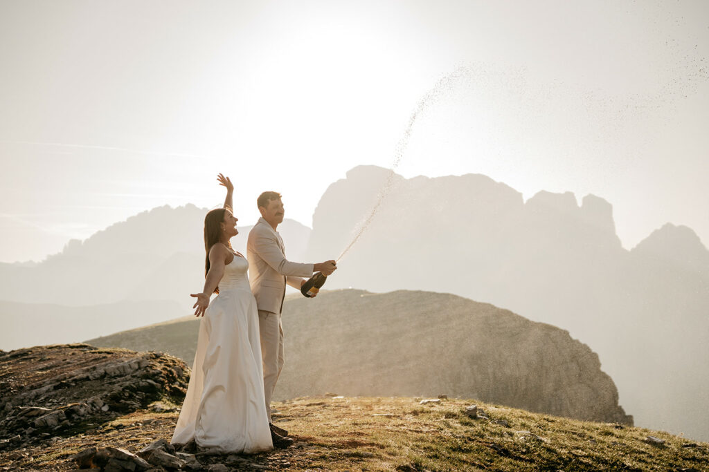 Couple celebrating with champagne in mountains.