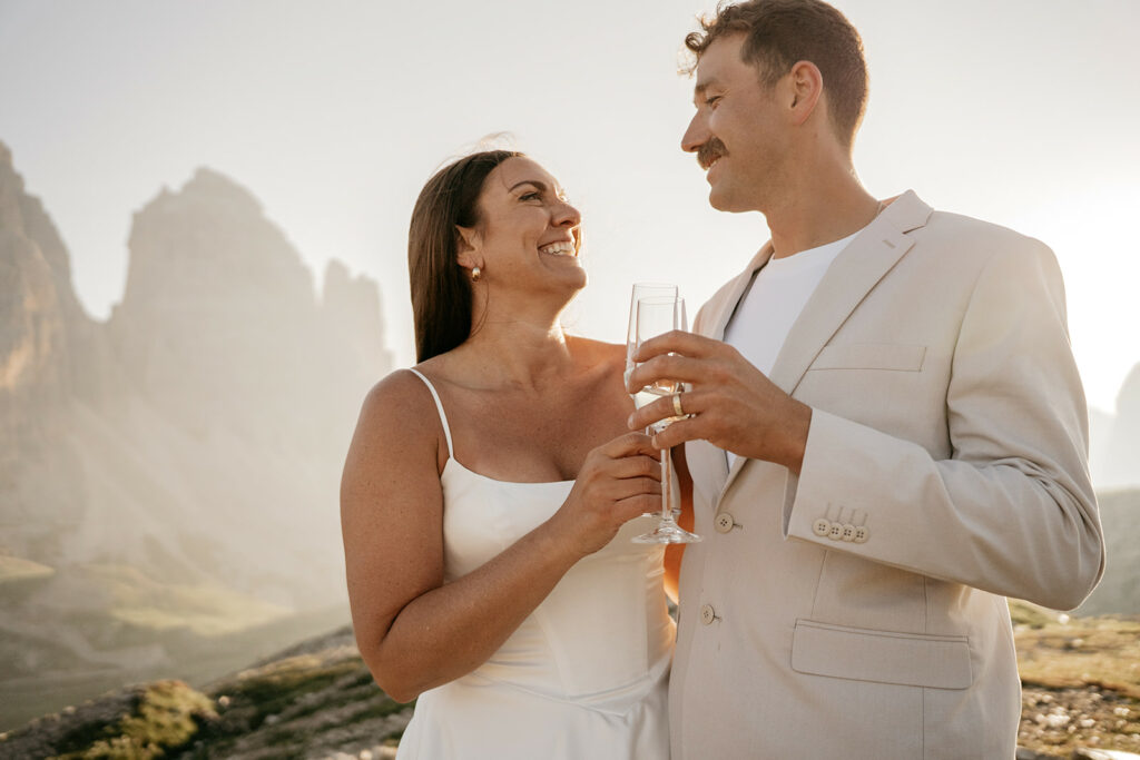 Couple celebrating with champagne in scenic mountains.