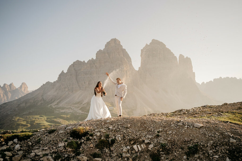 Couple celebrating with champagne in mountain landscape.