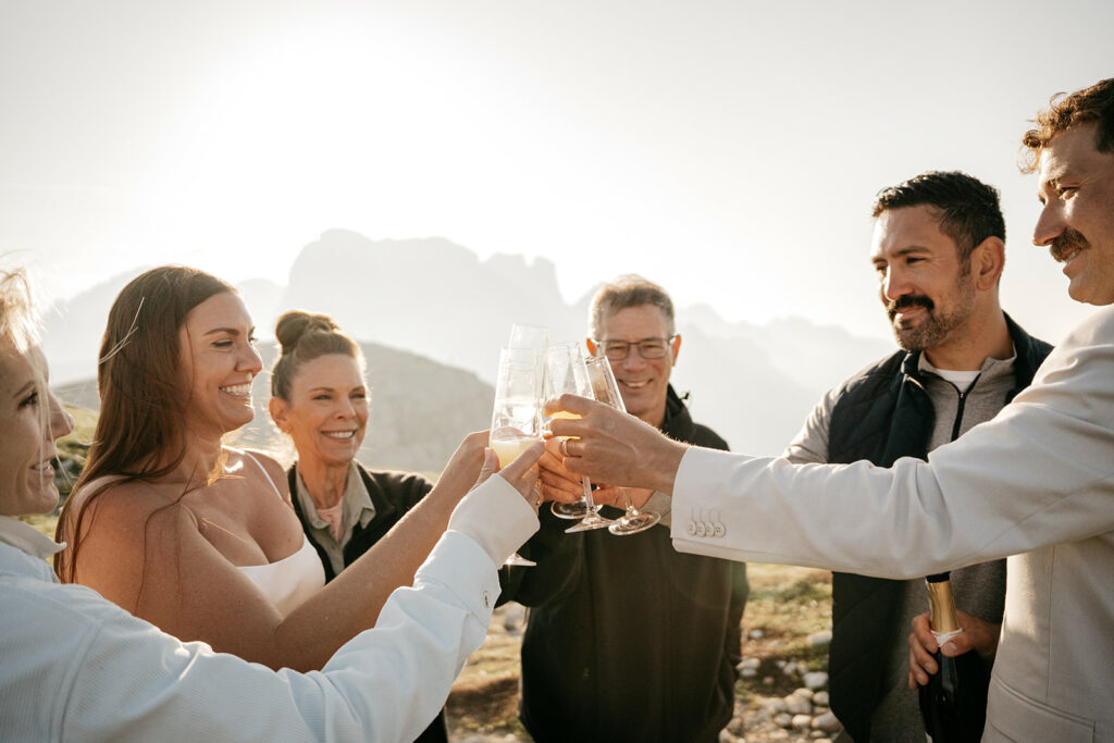 Group celebrating with champagne outdoors in sunlight.