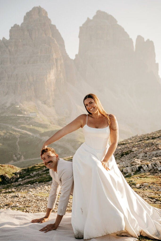 Bride and groom pose playfully in mountain setting.