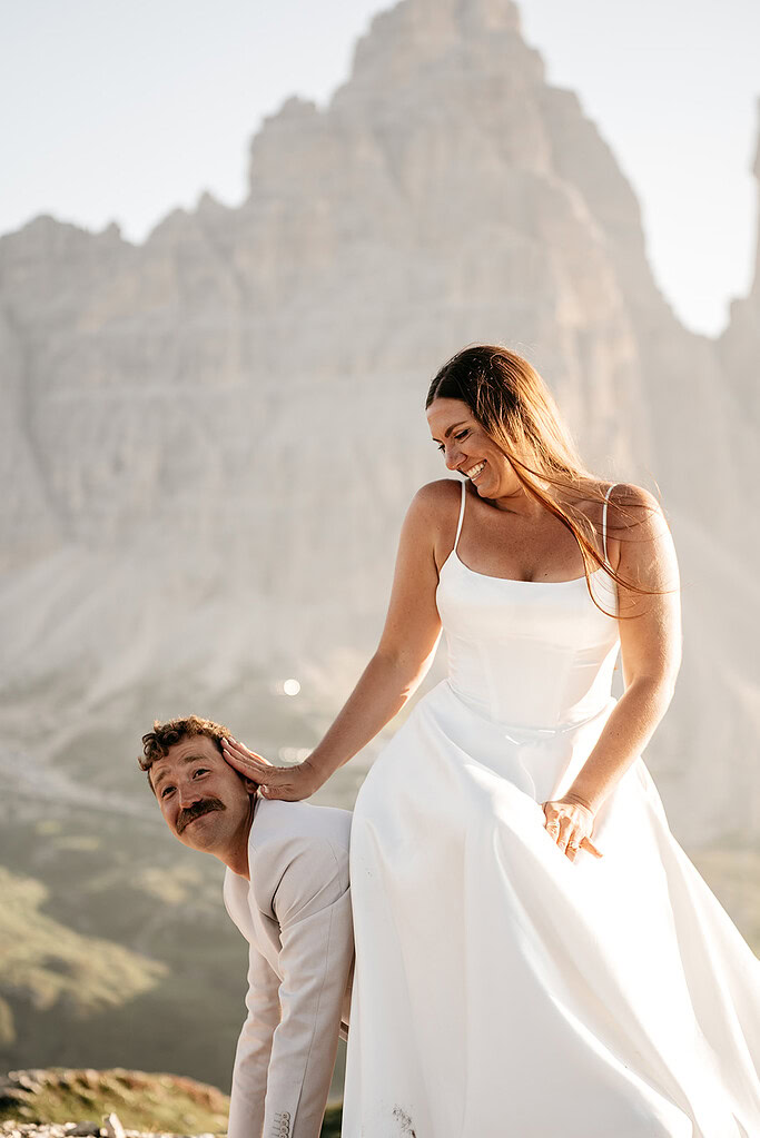 Bride playfully posing with groom in mountains