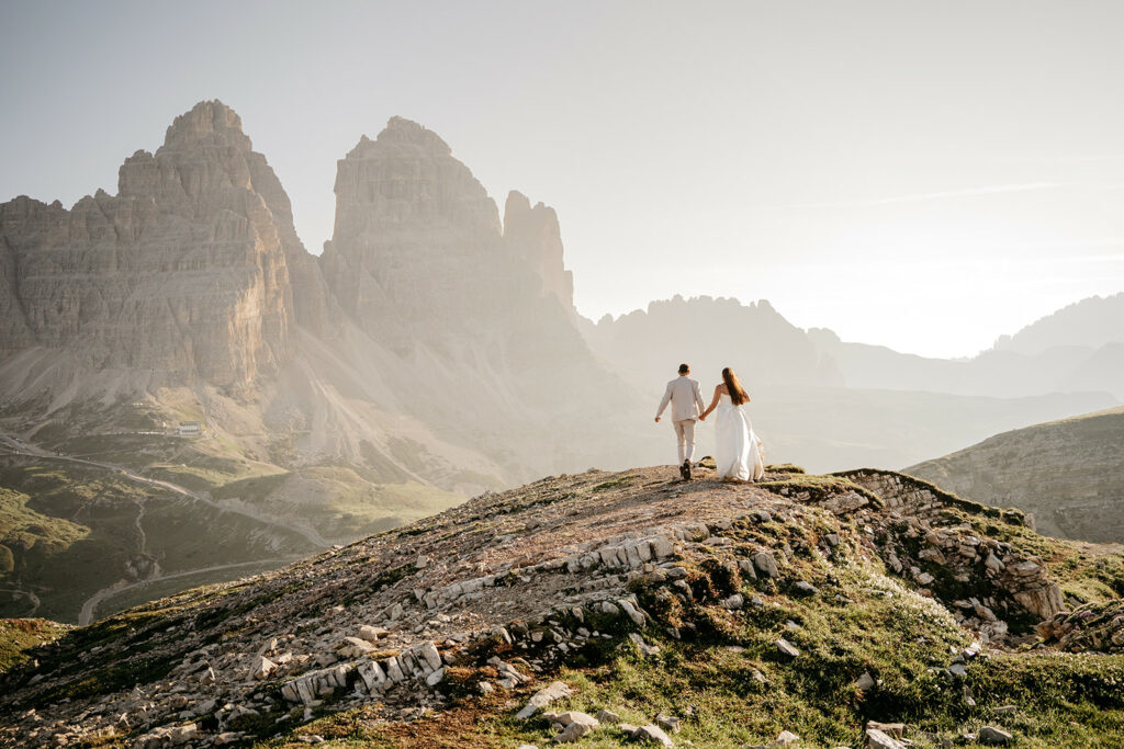 Couple walking on mountain landscape at sunrise.