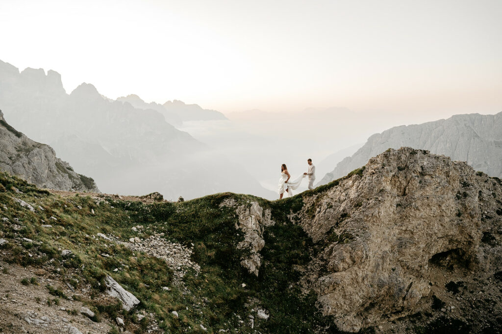 Couple walking along mountain ridge at sunset.