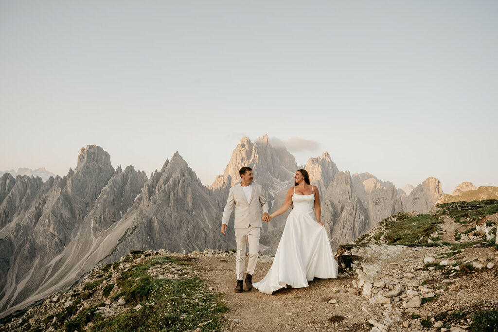 Couple in wedding attire, mountains in background.