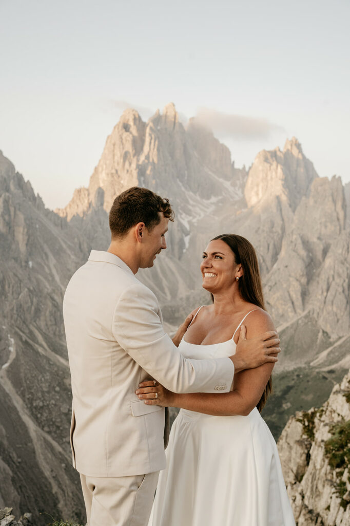 Couple embraces with mountains in the background.