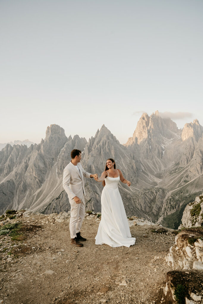 Couple dancing on mountain top in wedding attire.