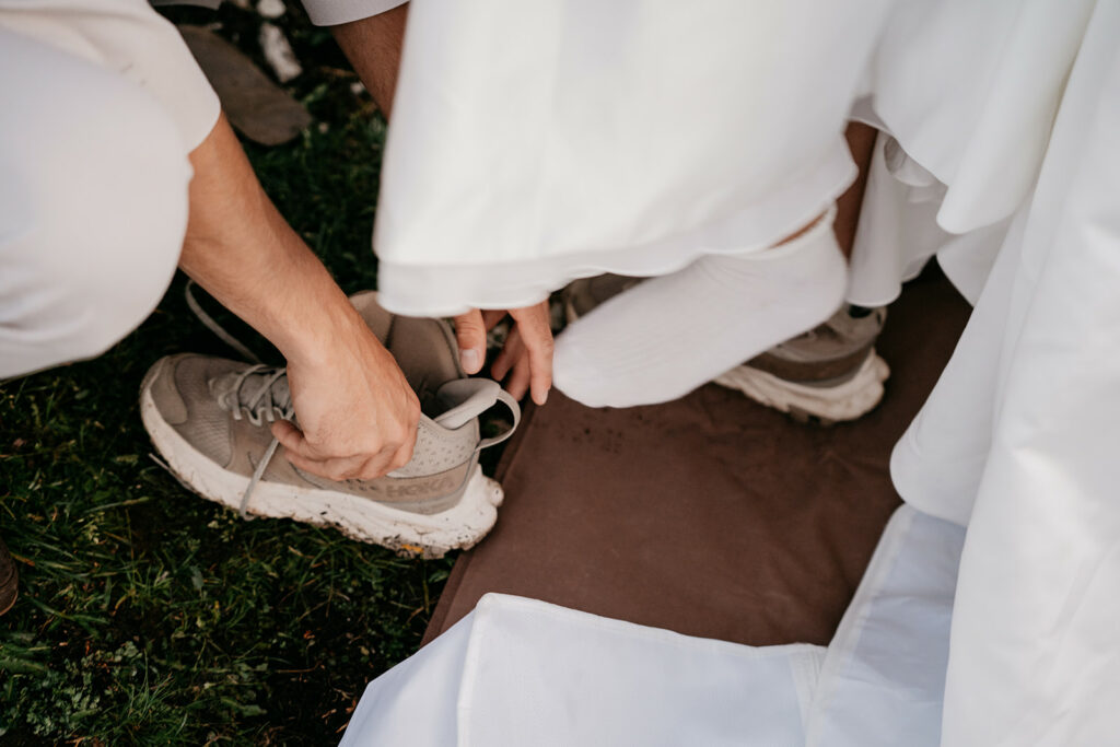 Person helping another put on shoes outdoors