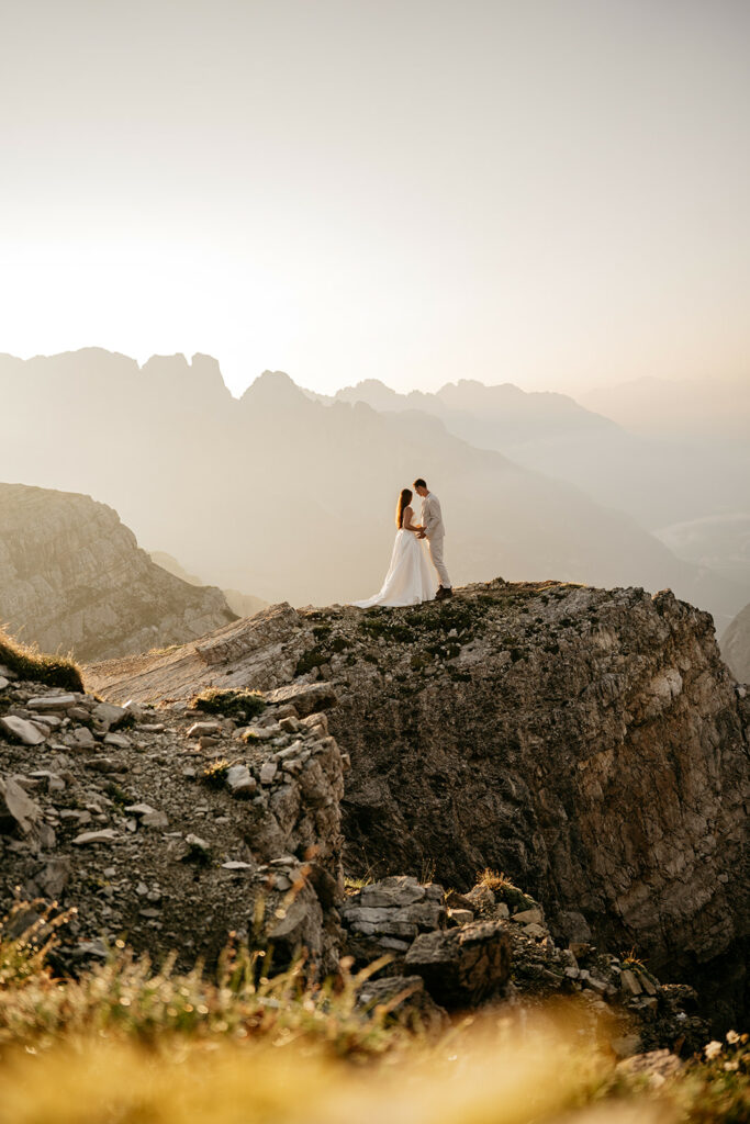 Couple on mountain cliff at sunset.
