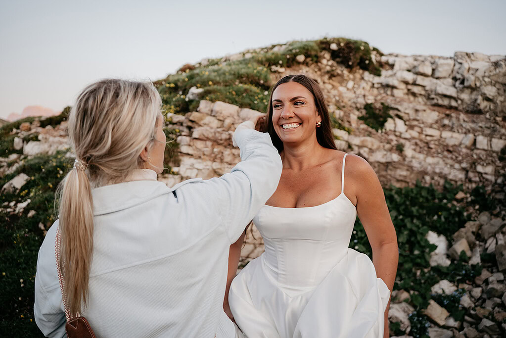 Bride smiling in outdoor setting with friend.