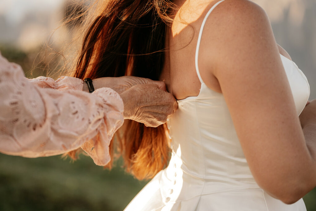 Woman helping bride with wedding dress