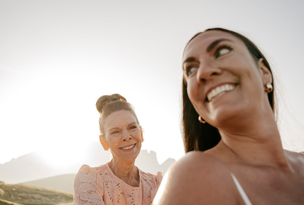 Two women smiling outdoors, sunny day