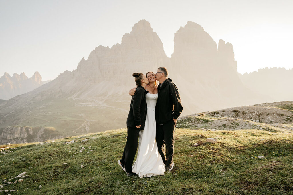 Bride with family in mountain landscape at sunset.