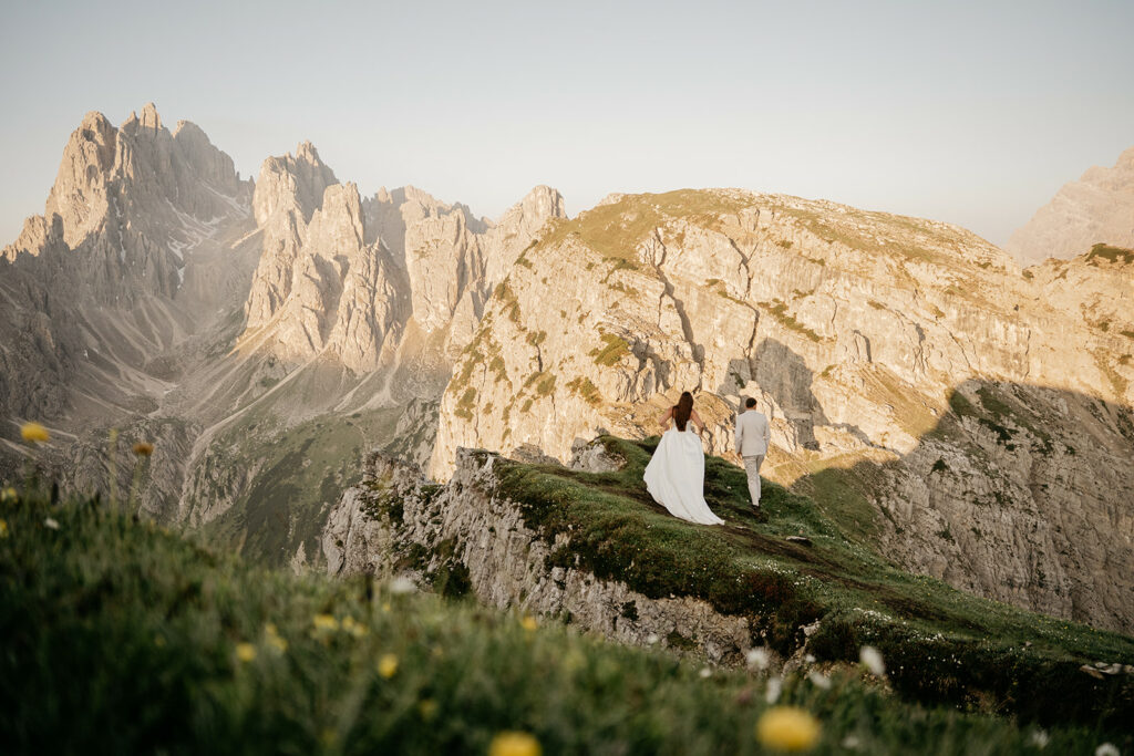 Couple hiking on mountain trail at sunset.