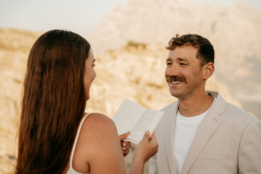 Couple exchanging vows outdoors with notebook.