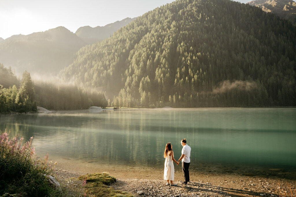 Couple holding hands by serene mountain lake