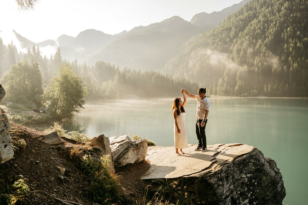 Couple dancing by a scenic mountain lake.
