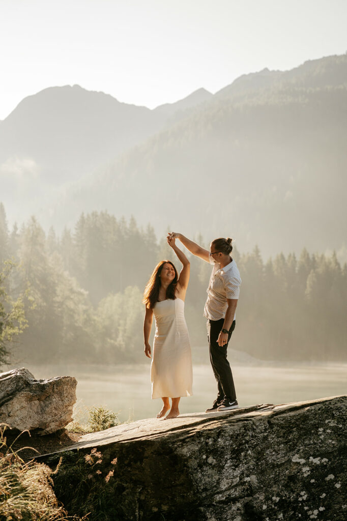 Couple dancing on mountain rock during sunrise.