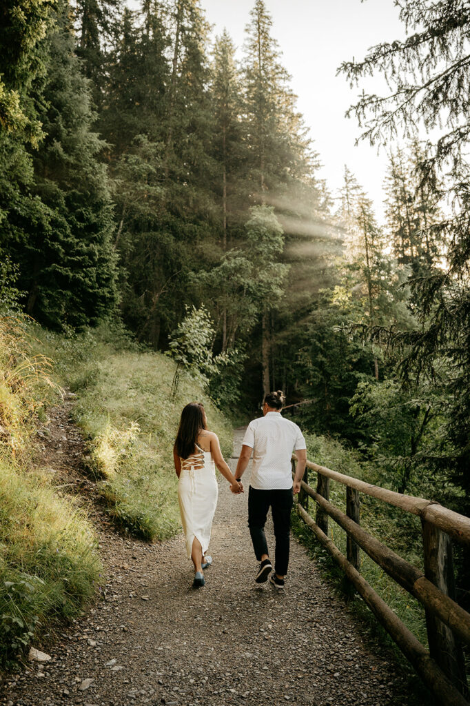 Couple walking hand-in-hand on forest trail