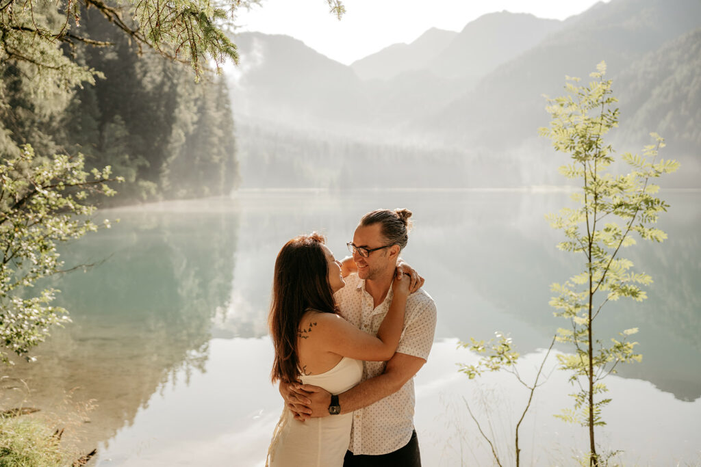 Couple embracing by a serene mountain lake.