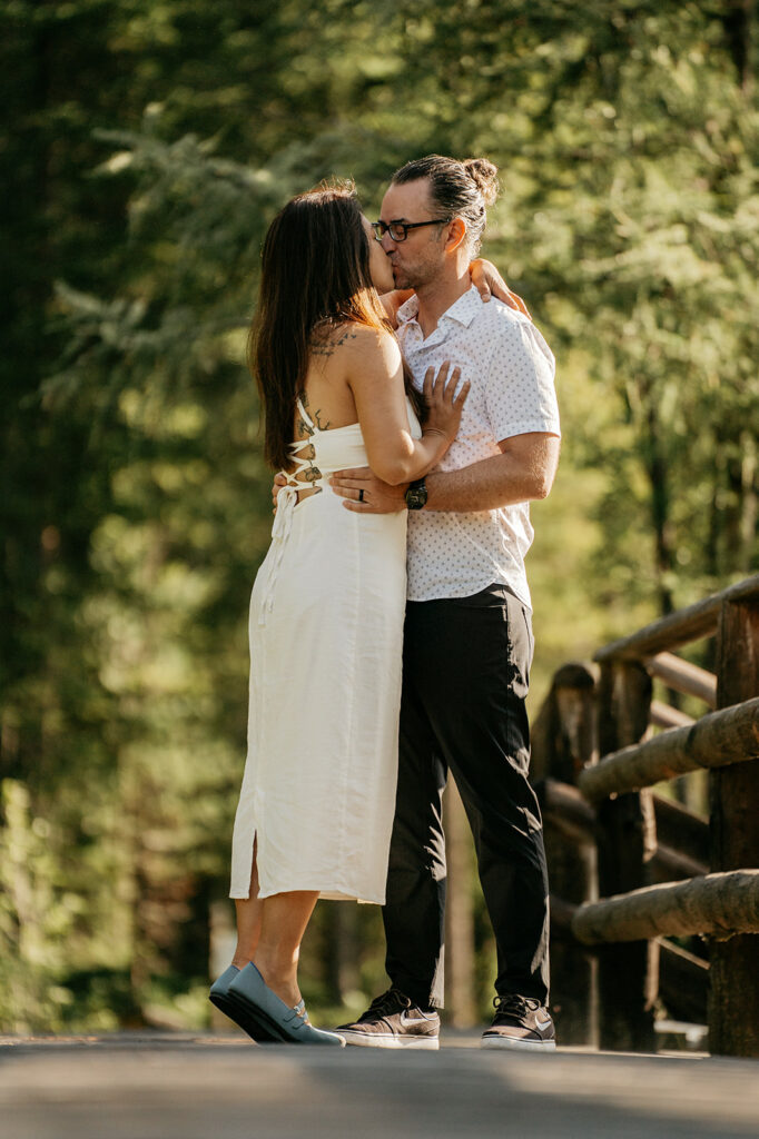 Couple kissing on a wooden bridge in nature.