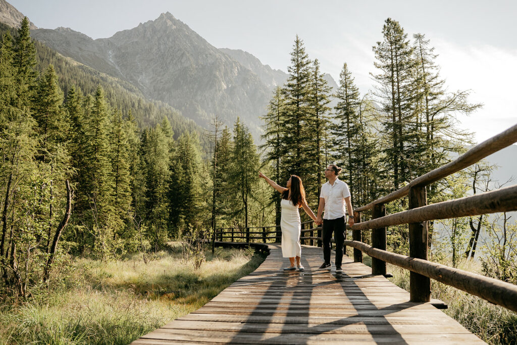 Couple walking on forest path, scenic mountain view.